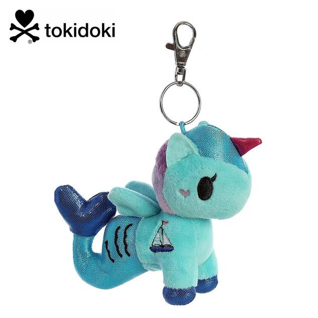 A keychain featuring a plush mermicorn in shades of blue, with a dark pink horn, and a boat design on the side.