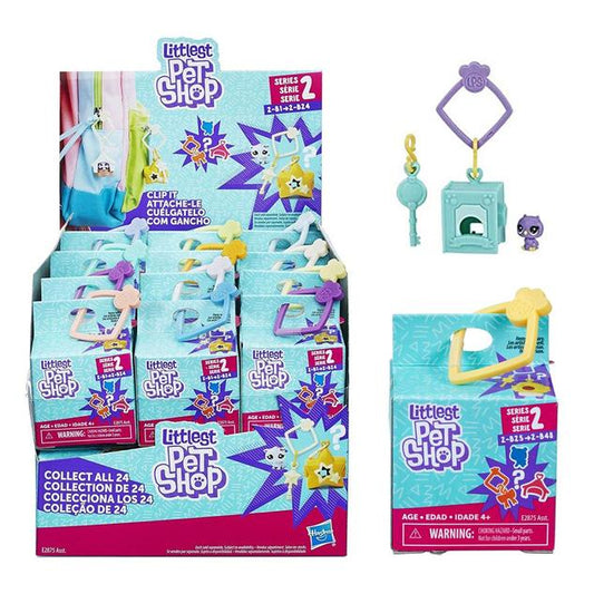 A light blue display box featuring Littlest Pet Shop blind boxes, each of which has a small plastic clip attached. The contents of one box is shown as a small plastic aqua box with matching key, and a purple cartoon kitten with exaggerated eyes.