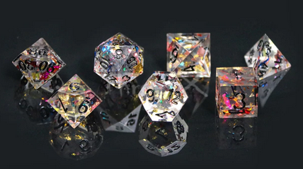 A set of clear polydice with sharp edges and black numbering. Inside are multi-coloured holographic flakes that refract the light.