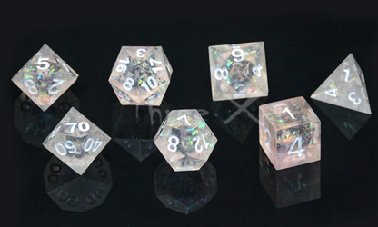 A set of clear polydice with sharp edges and white numbering. Inside are multi-coloured holographic flakes that refract the light.
